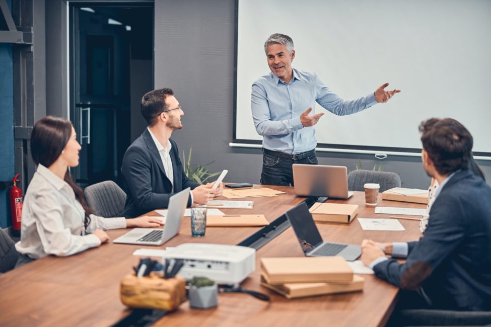 Managers discussing new startup project with boss in office e1701832887594